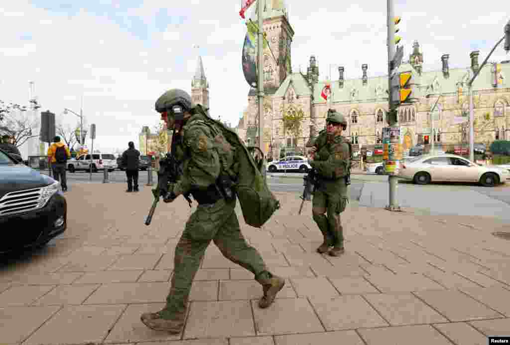 Armed RCMP officers head towards the Langevin Block on Parliament Hilll following a shooting incident in Ottawa.